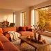 Modern apartment living room decorated with terracotta and burnt orange fall decor and warm sunlight.