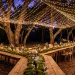Wide landscape of a whimsical forest backyard wedding with fairy lights and mossy tables.