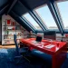 Wide shot of a productive attic office featuring navy blue walls and a bold red desk with skylights.