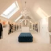 Luxurious boutique-style attic wardrobe with white custom cabinets, sloped ceilings, and a crystal chandelier.