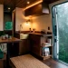 Luxury camper van interior with deep emerald green velvet seating and brushed brass lighting accents in a forest setting.