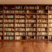 Wide panorama of a modern home library with floor-to-ceiling wooden bookshelves and a rolling library ladder.