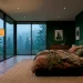 Moody forest green master bedroom with misty forest view and velvet textures.
