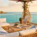 Luxurious coastal patio with stylish rattan furniture and ocean view at sunset.