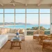 Breezy coastal grandmother sunroom with white linen furniture, rattan accents, and blue hydrangeas.
