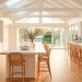 A wide sun-drenched white kitchen with marble counters and light wood floors for a breezy summer feel.