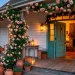 Wide landscape of a romantic cottage porch covered in climbing pink roses and glowing lanterns.