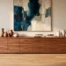 Wide shot of a luxury living room with a sleek walnut sideboard and minimalist decor on a light floor.