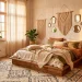 A wide panoramic shot of a dreamy boho bedroom with layered textiles, linen bedding, and rattan furniture in soft sunlight.