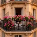 Wide shot of classic Parisian apartment building with ornate wrought iron balconies and flowers at sunset.