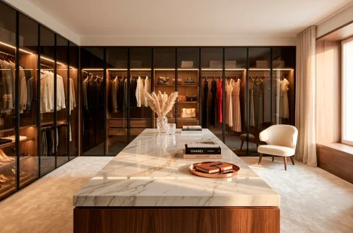 Wide view of a luxury minimalist dressing room with marble island and glass wardrobes.