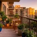 Lush urban balcony filled with hardy green plants and cozy furniture during golden hour.