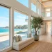 Luxurious light and airy coastal staircase with white risers, light wood treads, and sun-drenched entryway decor.