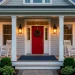 Wide landscape shot of a modern Americana porch with a red door, white trim, and navy accents at sunset.