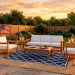 Wide shot of a decorated patio with layered outdoor rugs in navy and jute for a Memorial Day celebration.