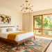 A wide horizontal shot of a sleek and inviting mid-century modern guest bedroom with walnut furniture.