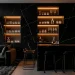 Luxurious wide-angle view of a modern monochromatic home bar with charcoal marble and designer bar stools.