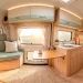 Wide-angle view of a serene camper van interior with soft sage green and oak wood pastel color palette.