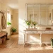 A wide, sunny country entryway featuring various distressed white farmhouse furniture and decor pieces.