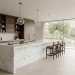 Wide landscape shot of a luxury modern kitchen with a marble waterfall island and dark oak cabinets.