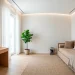 Wide landscape view of a modern combined home office and guest bedroom with sleek furniture and natural light.