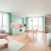 Wide panoramic view of a luxury studio apartment decorated in soft pastel mint and pink hues.