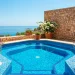 Wide Mediterranean patio featuring a vibrant blue tiled pond surrounded by terracotta pots and bougainvillea.