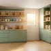 Wide panoramic shot of an organized modern utility room with sage green cabinets and stackable laundry units.