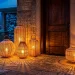 Wide shot of a snowy porch decorated with glowing oversized rattan lanterns and winter greenery.