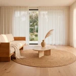 Wide-angle minimalist living room with warm wood accents, cream sofa, and soft natural sunlight.