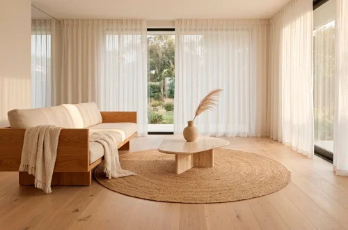 Wide-angle minimalist living room with warm wood accents, cream sofa, and soft natural sunlight.
