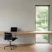 Wide view of an ultra-minimalist home office with a floating oak desk and natural lighting.
