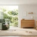 Modern minimalist nursery with space-saving convertible furniture and soft green accents in natural light.