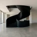 Wide view of a modern luxury home interior featuring a stunning monochromatic black architectural staircase.