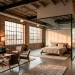 Wide horizontal view of a perfectly zoned urban loft studio apartment with high ceilings and industrial windows.