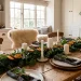 A cozy Scandinavian Christmas brunch table setting with an evergreen runner, white candles, and rustic wooden chargers.