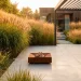 Beautiful modern backyard patio surrounded by tall ornamental grasses glowing in warm sunlight.