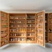 Organized custom fold-out small pantry system with wooden shelves and glass jars in a bright kitchen.