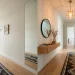 Modern narrow entryway with a large mirrored wall visually doubling the space and reflecting warm light.