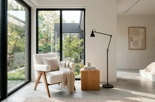 Serene modern minimalist bedroom reading nook with a white boucle chair and matte black floor lamp.