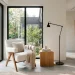Serene modern minimalist bedroom reading nook with a white boucle chair and matte black floor lamp.
