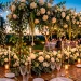 Oversized floral wedding table decorations with cascading greenery and glowing taper candles at twilight.