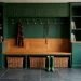 Wide landscape of a moody forest green mudroom with brass hooks, wood bench, and organized storage.