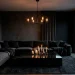 Moody living room decor featuring a matte black accent wall charcoal velvet sofa and industrial lighting fixtures