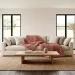 A plush cream sofa styled with a chunky dusty rose knit throw blanket in a sunlit modern living room.
