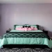 A dreamy pastel goth bedroom featuring lavender walls, pink neon bat lights, and black lace bedding.