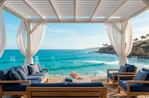 A wide 2:1 landscape of a luxurious white coastal pergola on a seaside deck with navy blue accents.