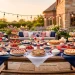 Wide view of a beautiful Memorial Day dessert table setup on an outdoor patio with festive treats and string lights.