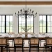 Wide view of a modern farmhouse dining room with wood table and black chandelier.