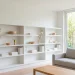 Clean minimalist white shelves styled for spring with greenery and neutral ceramic decor in a sunny living room.